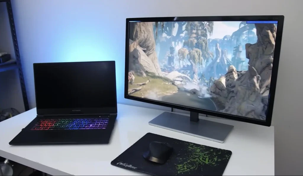 Laptop connected to an external monitor displaying a game, creating a dual-screen workspace for gaming, content creation, and productivity.