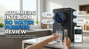 Atomberg Intellon RO Water Purifier installed in a modern kitchen with a smartphone showing the Atomberg app, highlighting an 8-month long-term review, adaptive filtration, and water quality monitoring.